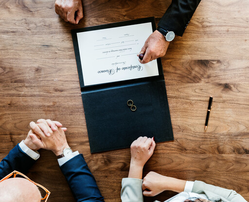 Braut und Bräutigam sitzen am Tisch und unterschreiben die Eheurkunde