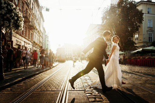 Hochzeitspaar läuft über Straßenbahnschienen